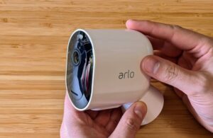 Safewise tester handling Arlo Pro 4 security camera attached to its magnetic mount.