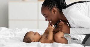 mom smiling at baby on bed