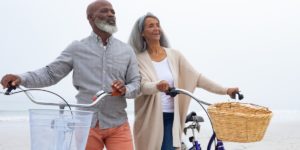 older couple on the beach with bicycles