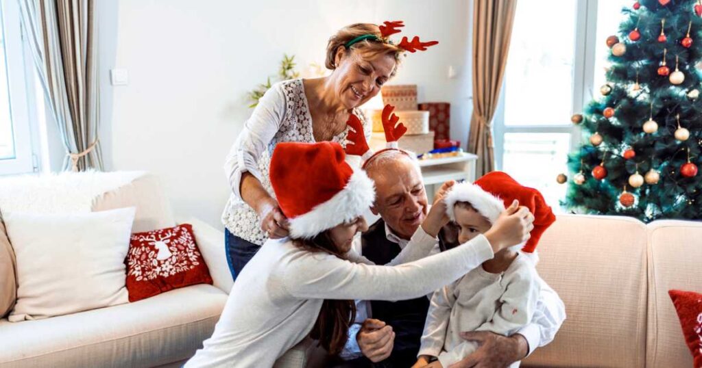 Grandparents And Grandchildren sitting on sofa in living room during Christmas holidays