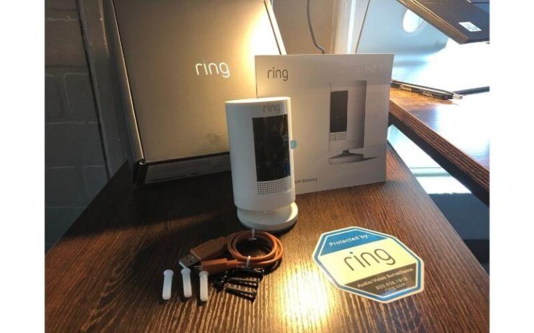 A Ring security camera on a table next to its packaging and accessories, ready for installation.