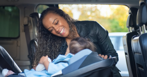 Mother securing baby in a rear-facing car seat