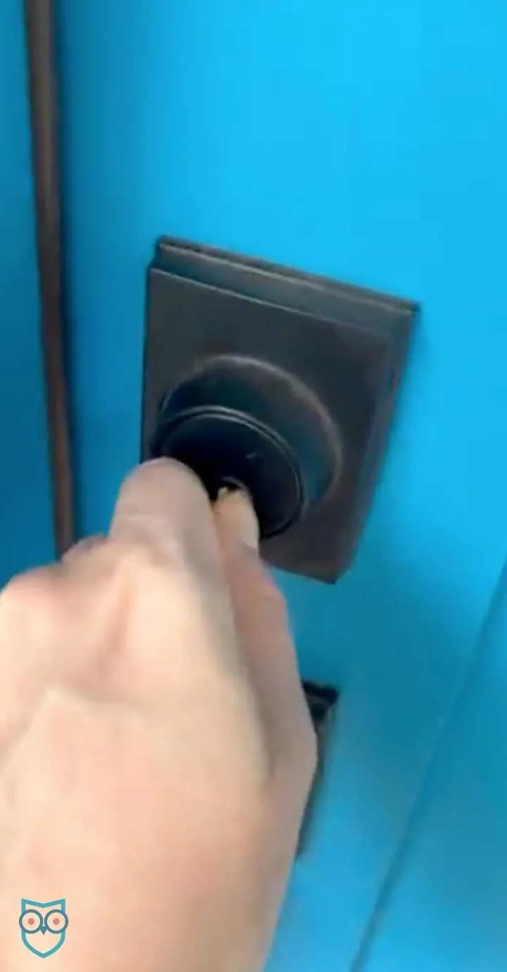 Hand unlocking a deadbolt on a blue door.