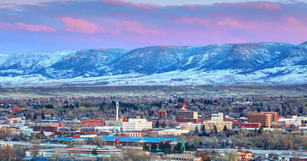 View of Casper, WY with mountains in the background and a pink and purple sky with clouds.