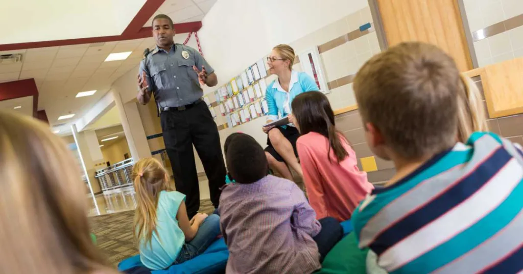 Police or school security officer speaking to young students stock photo