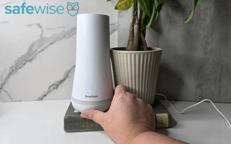 A person placing the SimpliSafe base onto a side table.
